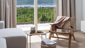 A balcony with a view of a lake and hills, a wicker chair with a blanket, a small table with a candle and a book. - Beautiful home in Seline (Seline)