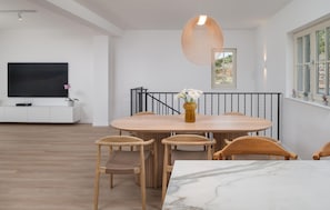 Ein moderner Essbereich mit einem Marmortisch, Holzstühlen und einer Hängeleuchte.
