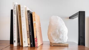 Een houten plank met een verzameling boeken en een heldere kwartskristal.