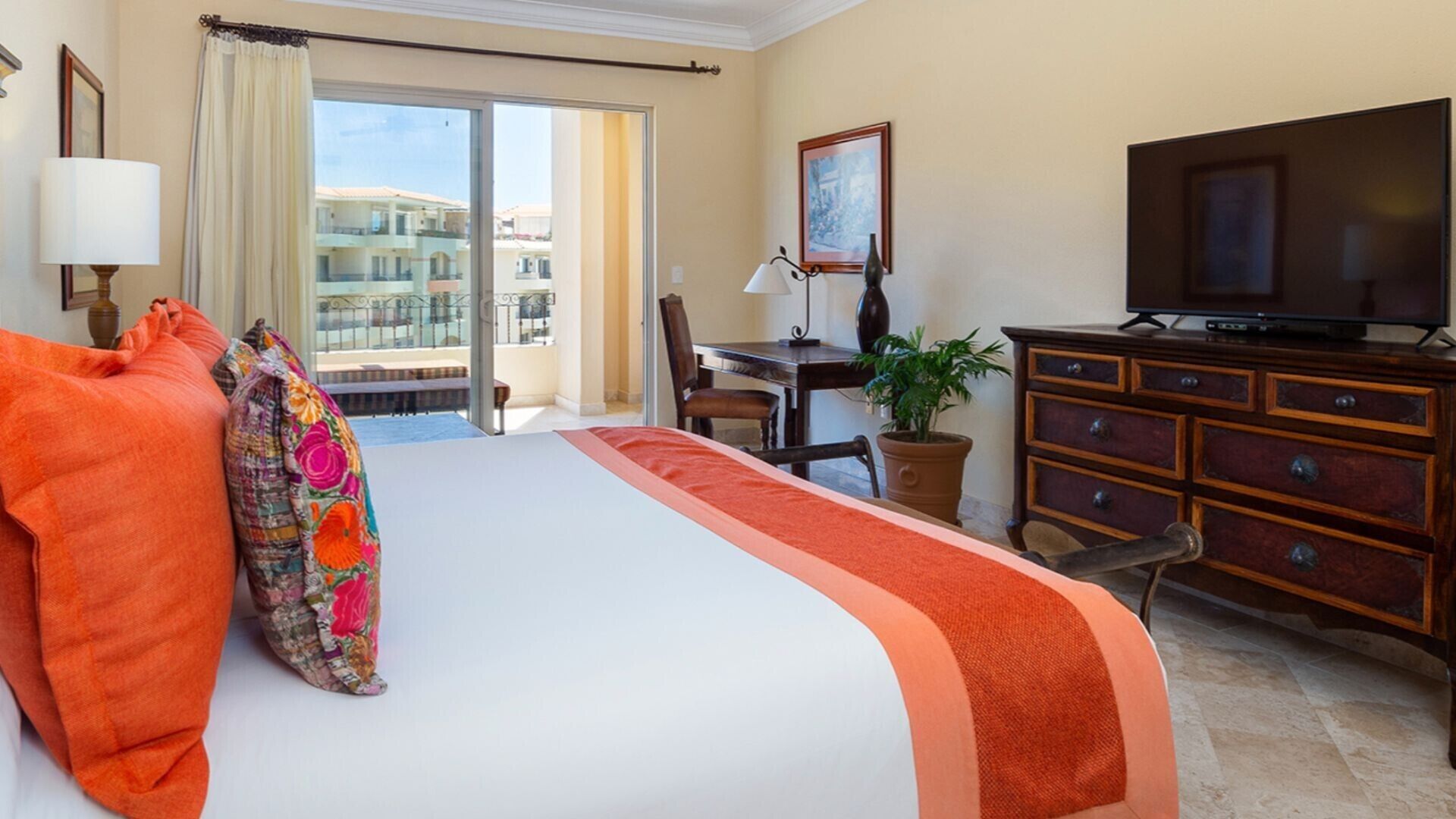 Habitación de hotel con cama, escritorio, televisión y vistas a edificios.