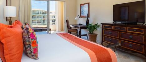 Habitación de hotel con cama, escritorio, televisión y vistas a edificios.
