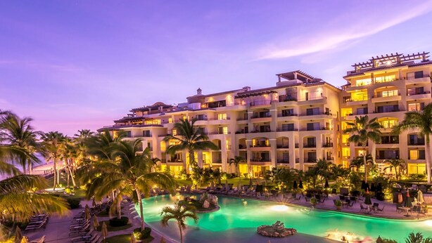 A multi-story hotel with a swimming pool, palm trees, and outdoor seating areas. - Luxury 2BR Suite at Villa La Estancia – Beachfront Pools, Spa & Sunsets (Cabo San Lucas)