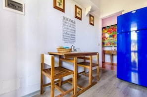 Eine Küche mit einem Holztisch, einem blauen Kühlschrank und einer Wand mit gerahmten Bildern und einem dekorativen Schild.