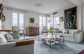 Un salon spacieux comprenant un canapé, des fauteuils, une table basse et un grand tableau.