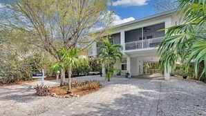 A two-story building with a covered patio area, surrounded by landscaped gardens and palm trees. - Villa Nueva (Key Largo)