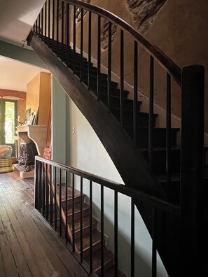A spiral staircase with a black railing, wooden steps, and a green wall. - Charming house in the heart of the Gironde (La Réole)