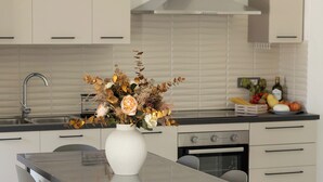 Une cuisine moderne dotée d’un îlot central, de meubles blancs et d’une hotte de cuisine en acier inoxydable.