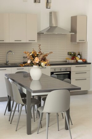 A modern kitchen with a central island, white cabinets, and a stainless steel range hood. - DreamFrame, a fantastic holiday in Agerola next to the Path of (Pianillo)