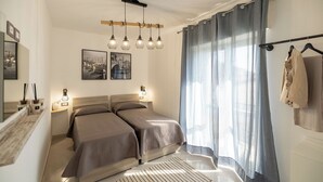 Une chambre à coucher moderne, dotée d’un grand lit, de lampes de chevet et offrant une vue sur l’extérieur à travers de fines rideaux.