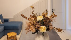 Une table à manger avec un vase de fleurs au centre, un canapé bleu et un escalier en arrière-plan.