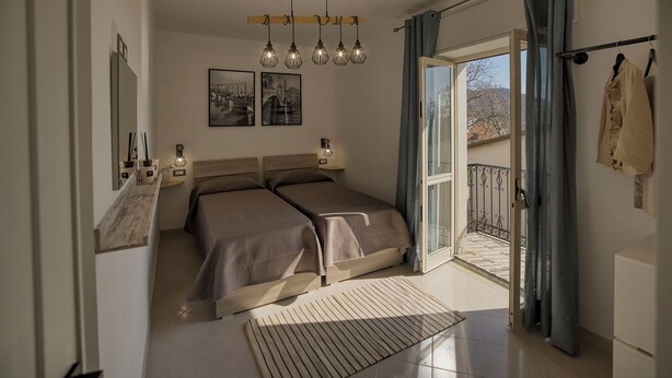 Une chambre avec deux lits, un balcon avec vue et une grande fenêtre.