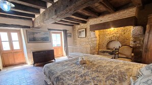 Een rustieke kamer met een bed, een open haard en stenen muren.