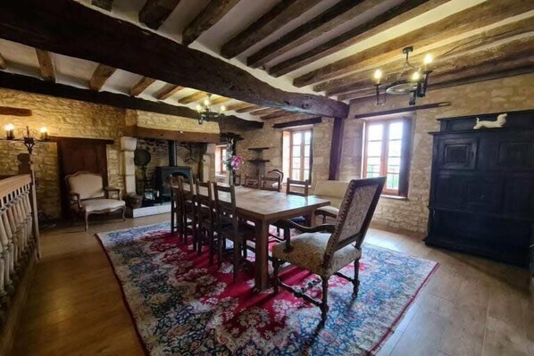 Ein rustikaler Essbereich mit Holztisch und -stühlen, einem gemusterten Teppich und sichtbaren Holzbalken an der Decke.