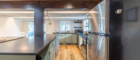 Une cuisine moderne dotée d’un îlot central, d’appareils électroménagers en acier inoxydable et d’un plancher en bois.