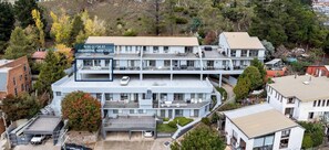 A multi-story hotel with a flat roof, a parking area, and a sign indicating its address. - The Summit 8 Great Views (Jindabyne)