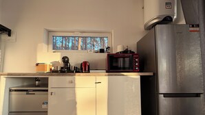 Una cocina compacta con microondas integrado, cafetera y refrigerador.