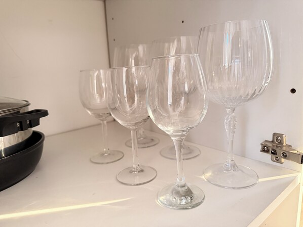 Una encimera de cocina con cuatro copas de vino y una olla negra.