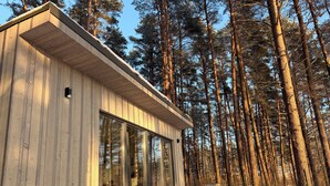 Una cabaña de madera con ventanas amplias, rodeada de un bosque.