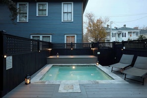 A swimming pool with a wooden deck, lounge chairs, and a fence. - Charming Victorian Home | Cocktail Pool (Savannah)