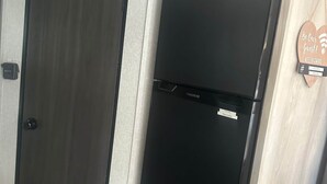 A room with a black refrigerator, a door with a handle, and a wall-mounted sign with a Wi-Fi symbol.
