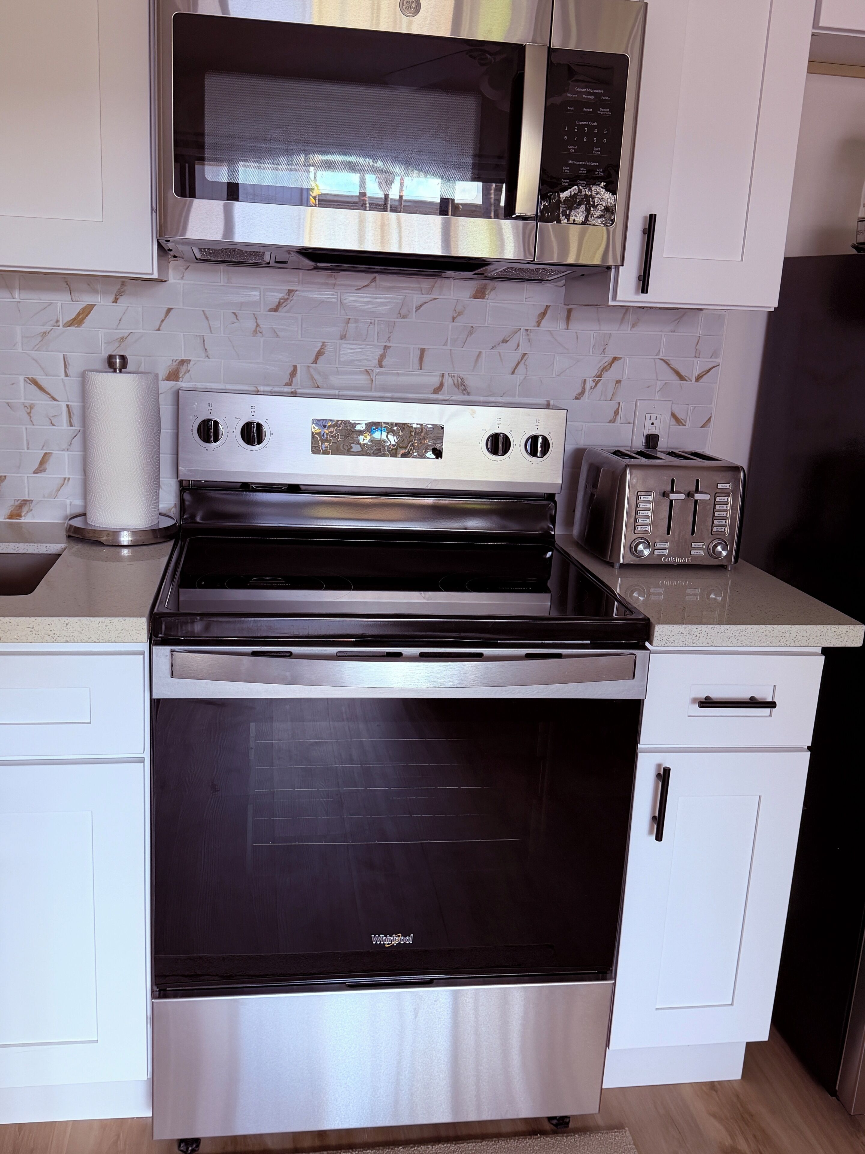 A kitchen with a stainless steel stove, oven, microwave, and toaster.