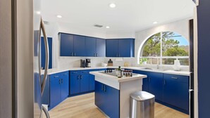 Una cucina moderna con mobili azzurri, un'isola centrale e un cestino in acciaio inossidabile.