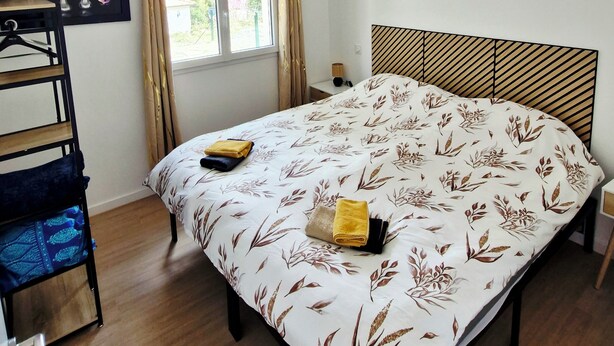 Un dormitorio con cama, ventana con cortinas, lámpara colgante y estante con jarrones.