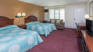 A hotel room with two beds, a sofa, a TV, and a desk.