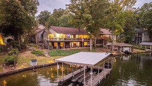 A lakeside property with a dock, a covered seating area, and multiple buildings with outdoor lighting. - The Breakaway on Lake Hamilton | Hot Tub, Kayaks! (Hot Springs National Park)