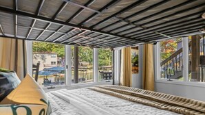 A room with a bed, large windows, and a view of a dock and outdoor area. - The Breakaway on Lake Hamilton | Hot Tub, Kayaks! (Hot Springs National Park)