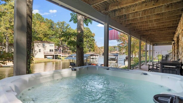 A hot tub area with a view of a lake and buildings in the background. - The Breakaway on Lake Hamilton | Hot Tub, Kayaks! (Hot Springs National Park)