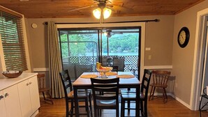 Ein Essbereich mit Holztisch und Stühlen, einem Deckenventilator und Blick durch die Glastür.