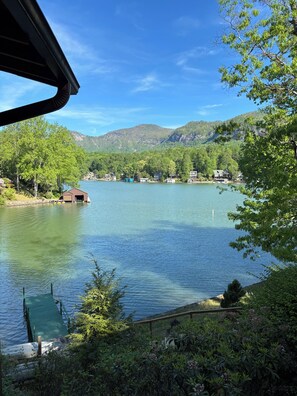 A lake with houses on the shore, surrounded by trees and hills.