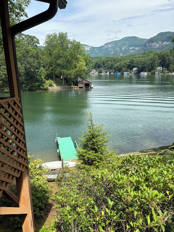 A lakeside view with a dock, a small building, and houses in the background.