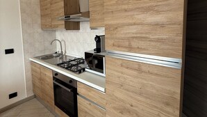 Una cucina moderna con mobili in legno, un piano di lavoro in acciaio inossidabile, un fornello a gas e un forno a microonde.