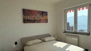 Una camera da letto con un letto, un comodino, una finestra vista e un quadro appeso al muro.