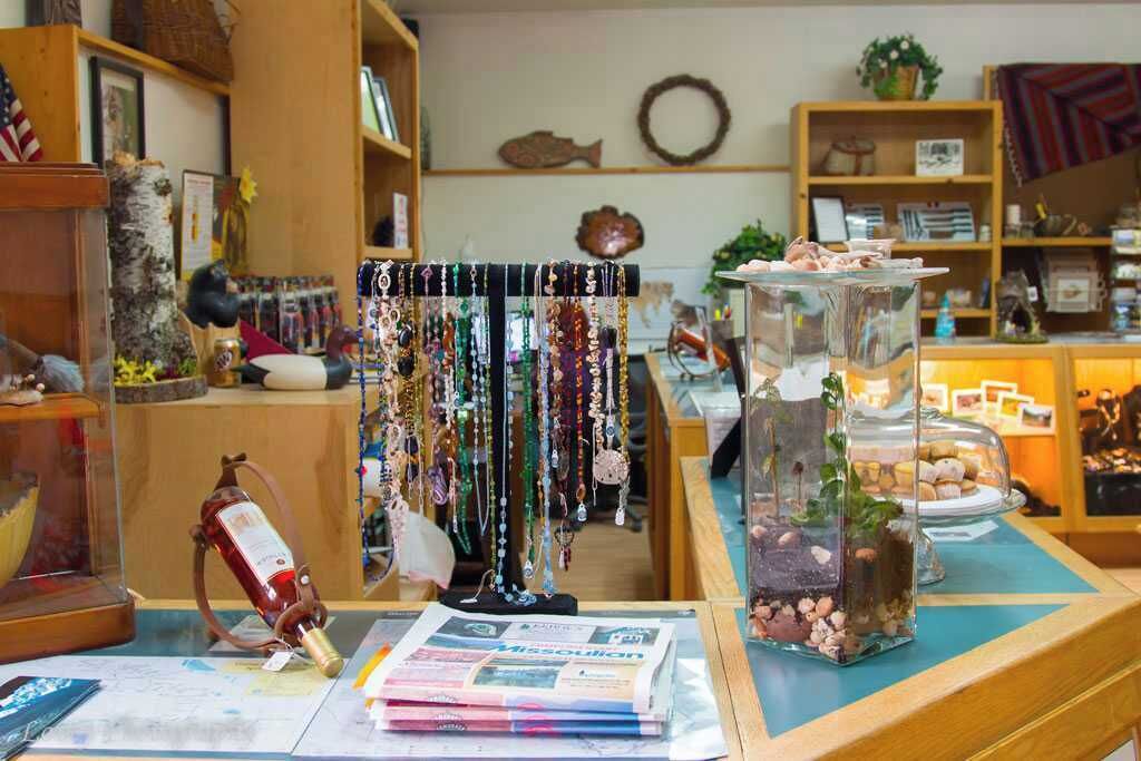 Una joyería con varios artículos expuestos, incluyendo collares, una decoración de pez y un terrario de vidrio con plantas.