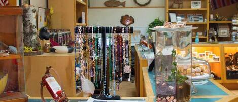 Una joyería con varios artículos expuestos, incluyendo collares, una decoración de pez y un terrario de vidrio con plantas.