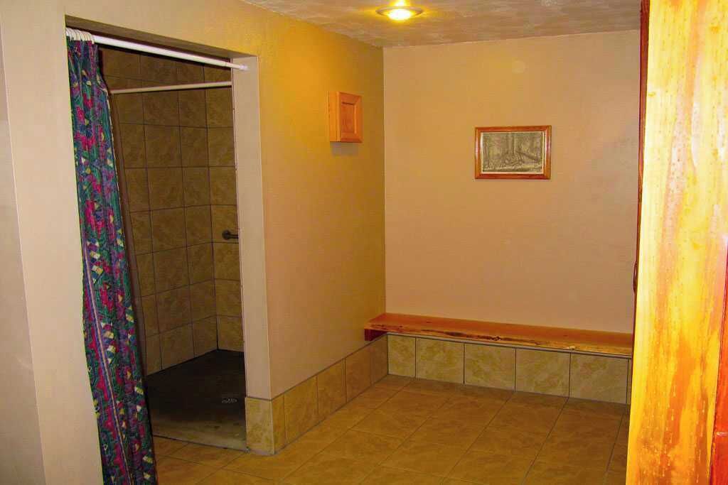 Un baño con ducha, un banco y un cuadro en la pared.
