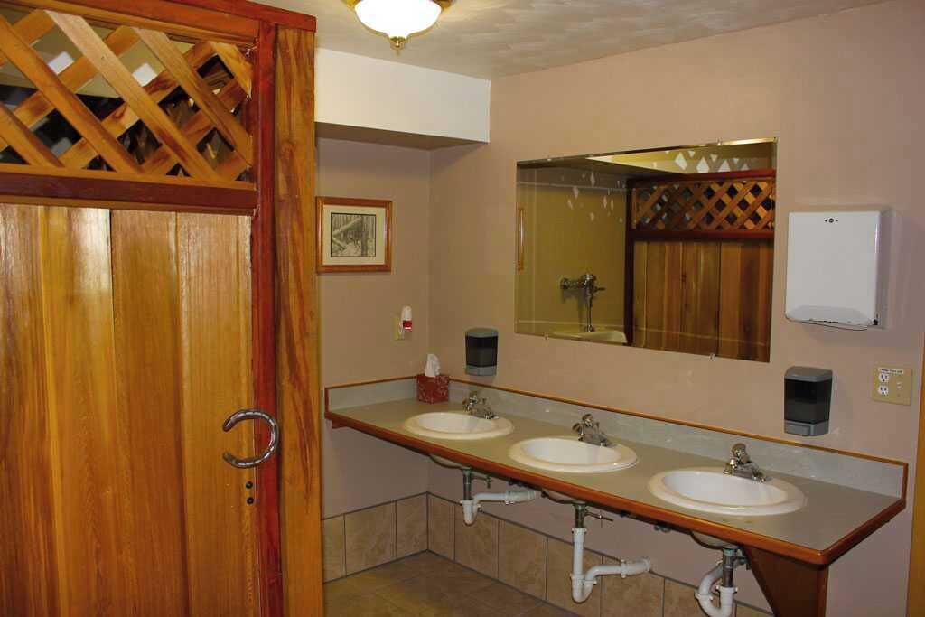 A bathroom with two sinks, a wooden door, a mirror, and a hand dryer.