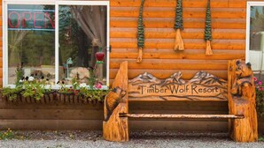A wooden bench with a mountain design and the text "Timber Wolf Resort" on a log cabin wall.