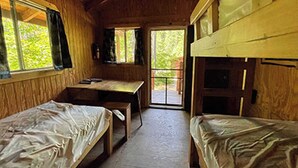 Una cabina con due letti a castello, una scrivania in legno e una finestra con tende.