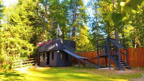 A small cabin with a wooden deck and a staircase leading to a wooden platform. - Cute Camper on FHU Site in Beautiful Campground (Hungry Horse)