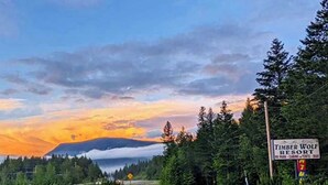 A sign for Timber Wolf Resort with a view of a mountain and sunset. - Lodge Room with Views of Glacier NP (Hungry Horse)