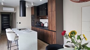 A modern kitchen with a central island, wooden cabinets, and a black range hood. - One of a kind villa 2+1 guests with heated pool and indoor wellness area (Svetvincenat)