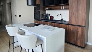 A modern kitchen with a central island, two bar stools, a coffee machine, and wooden cabinets. - One of a kind villa 2+1 guests with heated pool and indoor wellness area (Svetvincenat)