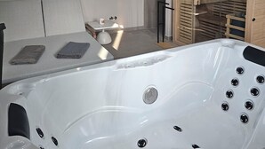 A modern bathroom with a large white bathtub, a wooden cabinet, and a small table with towels. - One of a kind villa 2+1 guests with heated pool and indoor wellness area (Svetvincenat)