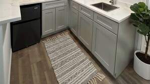 Una cocina moderna con gabinetes grises, una encimera blanca, lavavajillas integrado y un lavabo.