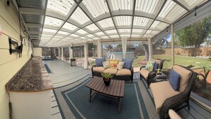 A covered patio area with outdoor furniture, a pool, and a view of the backyard.