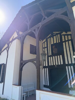 A traditional half-timbered building with a white facade and dark wooden beams, a bench outside, and a hanging lantern.